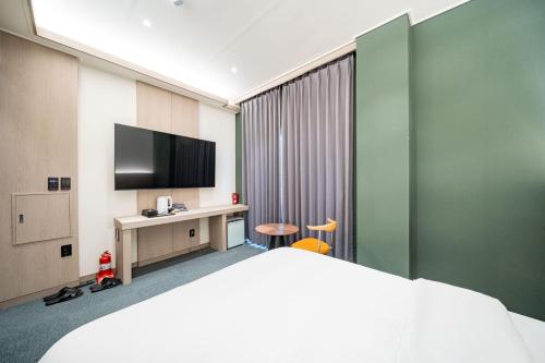 a hotel room with a bed and a flat screen tv at Hound Hotel DaeGu in Daegu