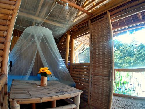 a wooden table with a vase of flowers on it in a cabin at Dumaguete Bamboo Cottages -Dauin in Dauin