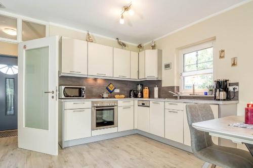 ツィングストにあるHuus Jetteの白いキャビネットとテーブル付きのキッチン