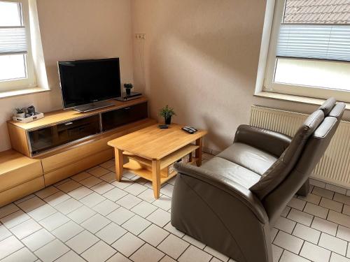 a living room with a tv and a chair and a table at Appartementhaus Schlagstein App3 in Kreuzau