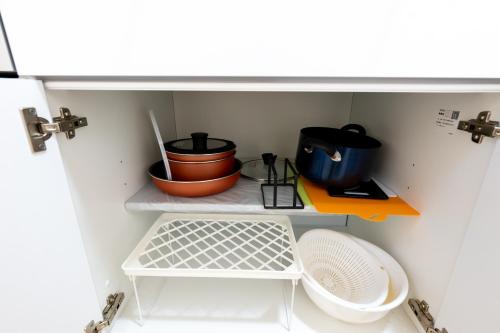 a small kitchen with a shelf with pots and pans at FINOA Residential Suite Higashikanamachi in Tokyo
