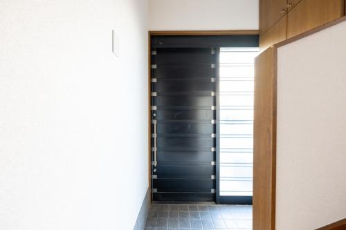 a hallway with a black door and a tile floor at FINOA Residential Suite Higashikanamachi in Tokyo