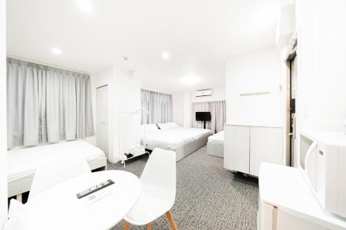 a hotel room with two beds and a table and chairs at GLOU Koiwa Tokyo - Economic APT in a Japanese Local Shopping Street, with Direct Access to Shinjuku & Akihabara in Tokyo