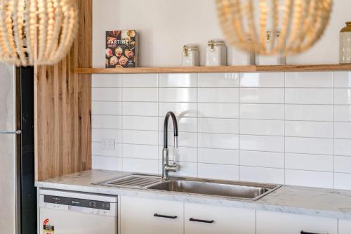 a kitchen with a sink and white tiled walls at 66 Neighbour Ave Goolwa - Linen Provided in Goolwa South