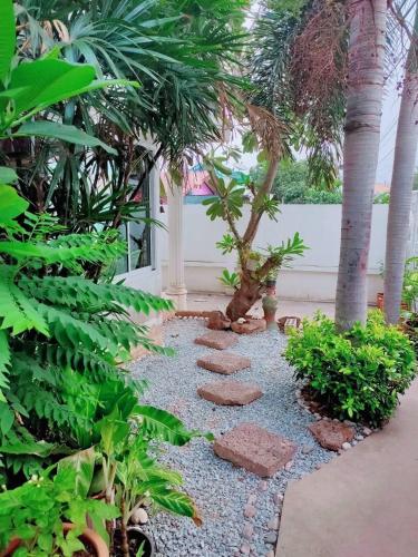 a garden with palm trees and stepping stones at Thongtalay Bed & Breakfast Koh Larn in Ko Larn