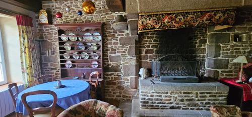 Cette chambre en pierre dispose d'une table et d'une cheminée. dans l'établissement Maison NORMANDE AUTHENTIQUE ERNESTINE, à Isigny-le-Buat