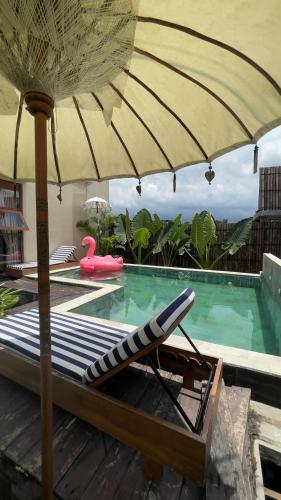 a pool with a chair and an umbrella and a swimming pool at The Phalosaa Villa in Ngaglik