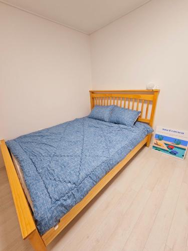 a bedroom with a wooden bed with a blue blanket at New 패밀리 & 친구 여행 모임 청결하고 쾌적한 넓은 신축아파트 주차 편리 쓰리룸 in Bucheon