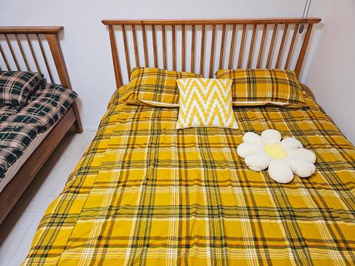 a yellow plaid bed with two white flowers on it at New 패밀리 & 친구 여행 모임 청결하고 쾌적한 넓은 신축아파트 주차 편리 쓰리룸 in Bucheon