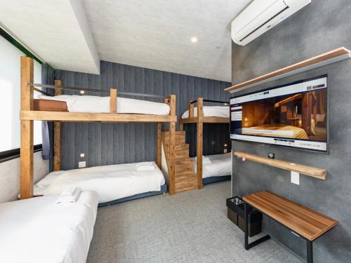 a room with three bunk beds and a tv at WELLSTAY Namba in Osaka