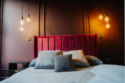 a bedroom with a bed with a red headboard and pillows at Stunning Town Centre Apartments with Spa facilities in Morpeth