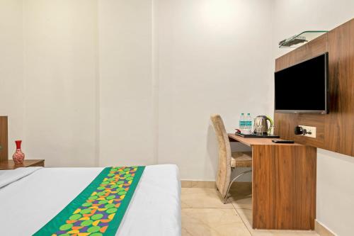a bedroom with a bed and a desk with a television at Treebo Elegant Palace in New Delhi