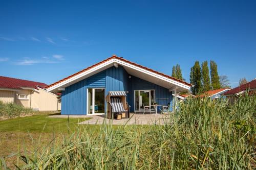 a blue house with two chairs in a yard at Typ A plus "Schoner" -Skipperhaus- in Pelzerhaken