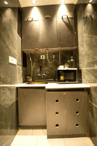 a kitchen with a sink and a microwave at Orsom Stays Sassy - Sector 42 in Gurgaon
