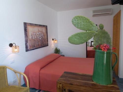 una camera da letto con un letto con copriletto rosso e un centrotavola di cactus di Hotel Lido Torre Egnazia a Monopoli