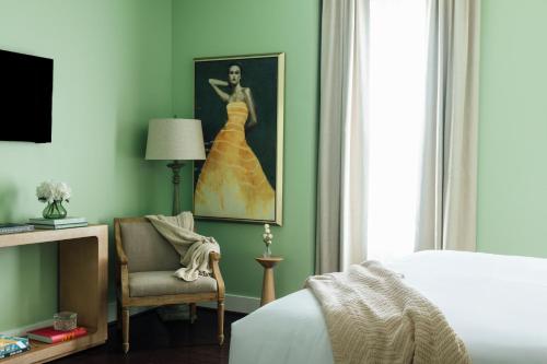 a bedroom with a bed and a chair and a painting of a woman at The Painted Lady in Birmingham