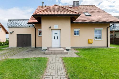 a house with a white door and a grass yard at Holiday House Mewa by Noclegi Renters in Zastań