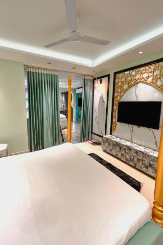 a bedroom with a large bed and a flat screen tv at Orsom Stays Sassy - Sector 42 in Gurgaon
