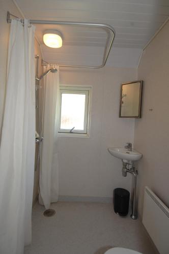 a white bathroom with a shower and a sink at Terrassen Camping & Cottages in Silkeborg