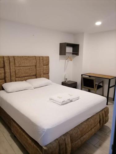 a bedroom with a large white bed and a desk at HOTEL GOLDEN CARTAGO in Cartago
