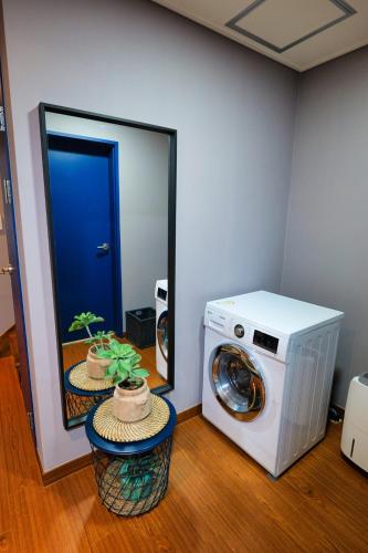 a washing machine in a room with a mirror at Hyeopjae MoonBeam in Jeju