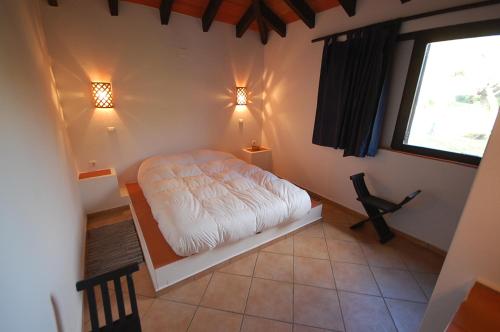 1 dormitorio con cama blanca y ventana en Pedras D'el Rei Villa V1, en Tavira