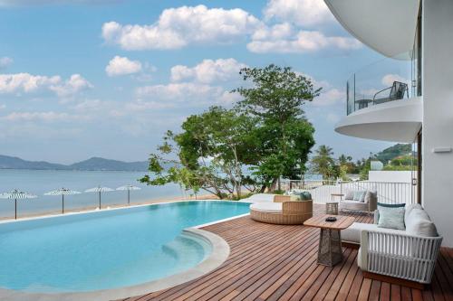 a pool with chairs and a table on a deck at Veranda Resort Phuket, Autograph Collection in Panwa Beach