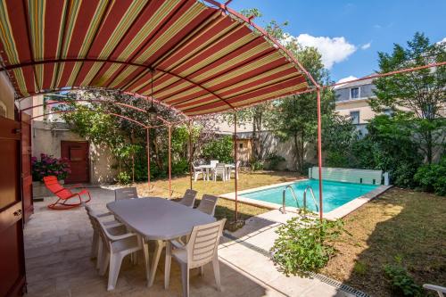 un patio avec une table et des chaises et une piscine dans l'établissement Maison Eugène centre-ville piscine jardin fibre garage, à Millau