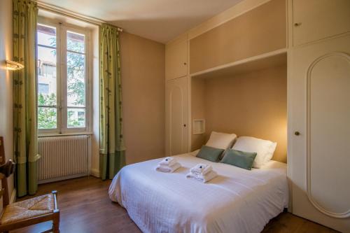 une chambre avec un lit blanc et une fenêtre dans l'établissement Maison Eugène centre-ville piscine jardin fibre garage, à Millau