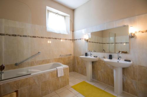 une salle de bain avec une baignoire, un lavabo et un miroir dans l'établissement Maison Eugène centre-ville piscine jardin fibre garage, à Millau