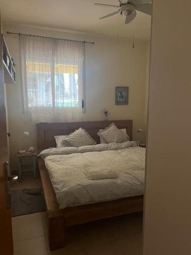 a bedroom with a bed with white sheets and a window at O&B Hospitality - אירוח אלף בית in Metsudat Menahem Ussishkin Alef