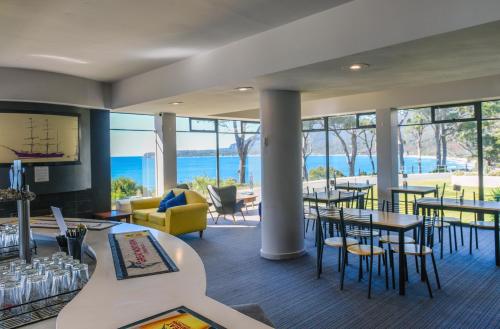 a restaurant with tables and chairs and a view of the ocean at Lufra Beachside Hotel in Eaglehawk Neck