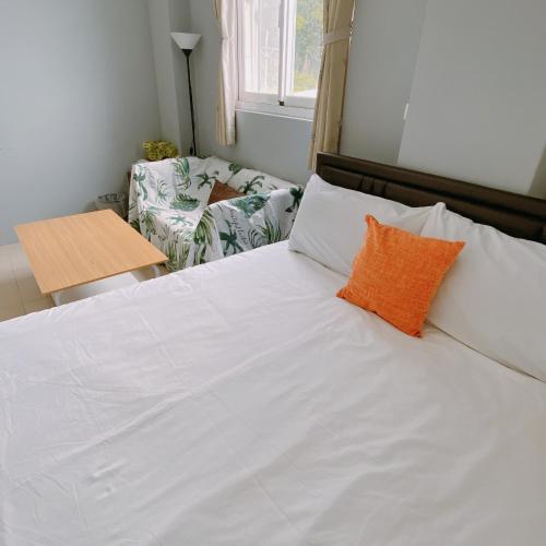a bed with white sheets and an orange pillow at 綠島夏御 微熱海岸 in Green Island