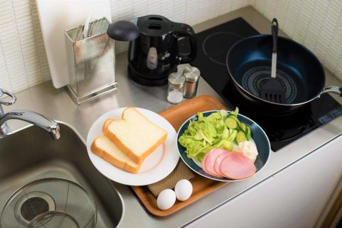 a sink with a plate of bread and a bowl of salad and eggs at GOZAN HOTEL & SERVICED APARTMENT Higashiyama Sanjo in Kyoto