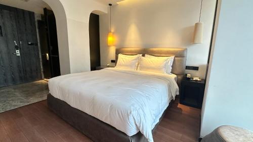 a bedroom with a large bed with white sheets and pillows at 柏高酒店-深圳公明广场地铁站店 in Bao'an