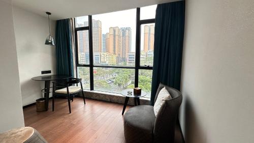 a room with a large window with a chair and a table at 柏高酒店-深圳公明广场地铁站店 in Bao'an