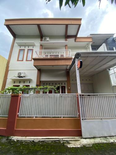 a house with a white fence in front of it at Ata Homestay Purwokerto in Purwokerto