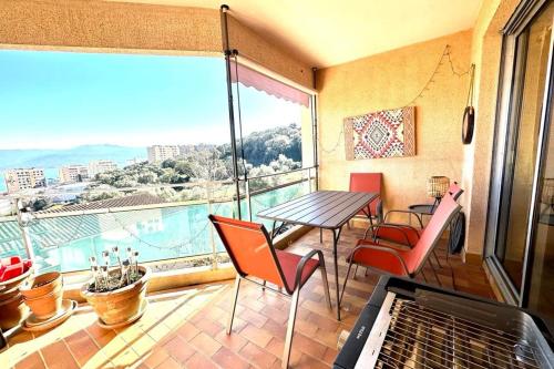 un balcon avec une table et des chaises et une grande fenêtre dans l'établissement Luminous T3 in the heights of Ajaccio, à Ajaccio