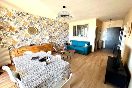 un salon avec une table et un canapé bleu dans l'établissement Luminous T3 in the heights of Ajaccio, à Ajaccio