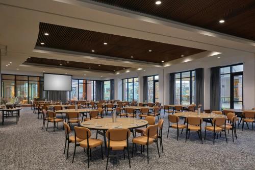 a conference room with tables and chairs and a screen at Asher Adams, Autograph Collection in Salt Lake City