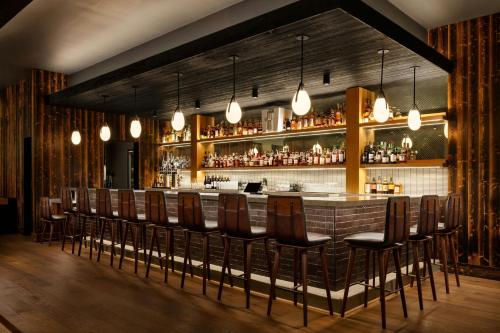 a bar with a row of chairs and lights at Moxy Asheville in Asheville