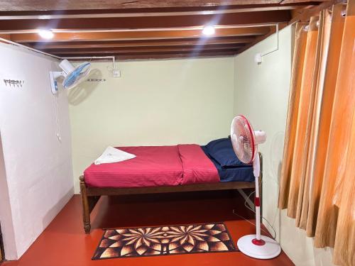 a small room with a bed and a fan at Grandpa's Vintage Home Stay in Madikeri