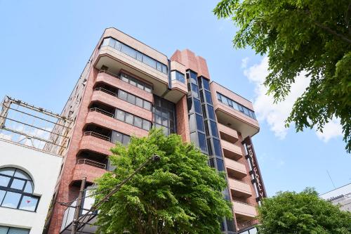 a tall red brick building with trees in front of it at Hotel Global View Hachinohe in Hachinohe
