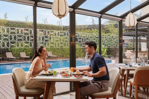 a man and woman sitting at a table in a restaurant at Courtyard by Marriott Goa Colva in Colva