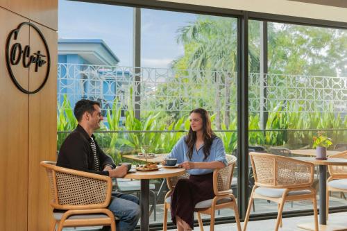 a man and woman sitting at a table in a restaurant at Courtyard by Marriott Goa Colva in Colva