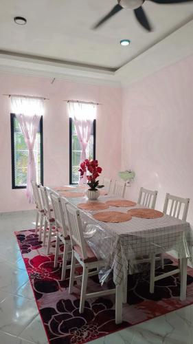 a dining room table with chairs and a vase of flowers at Teratak Falah Homestay in Sungai Buluh