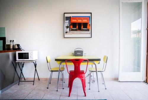 une table et des chaises dans une cuisine avec un tabouret rouge dans l'établissement Studio 60, à Sète