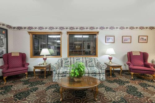 a living room with two chairs and a couch and a table at Super 8 by Wyndham Coshocton Roscoe Village in Coshocton