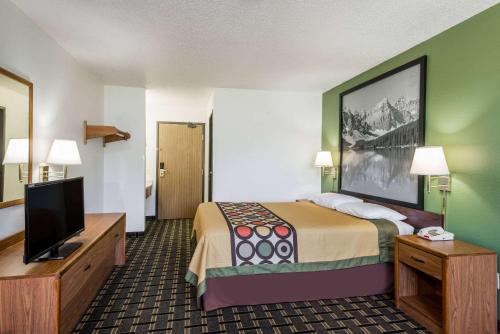 a hotel room with a bed and a flat screen tv at Super 8 by Wyndham Coshocton Roscoe Village in Coshocton