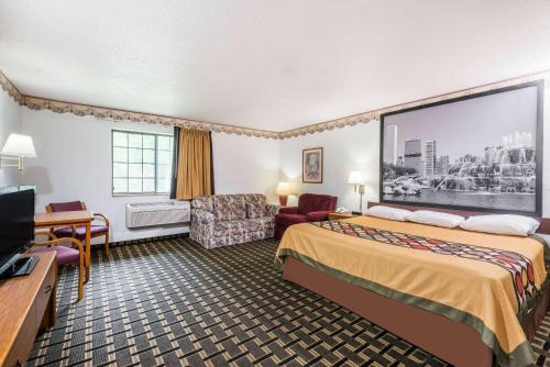 a hotel room with a bed and a flat screen tv at Super 8 by Wyndham Coshocton Roscoe Village in Coshocton